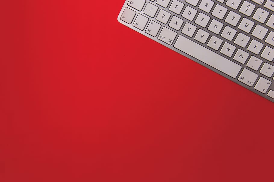 Wireless computer keyboard on a red background, technology, business