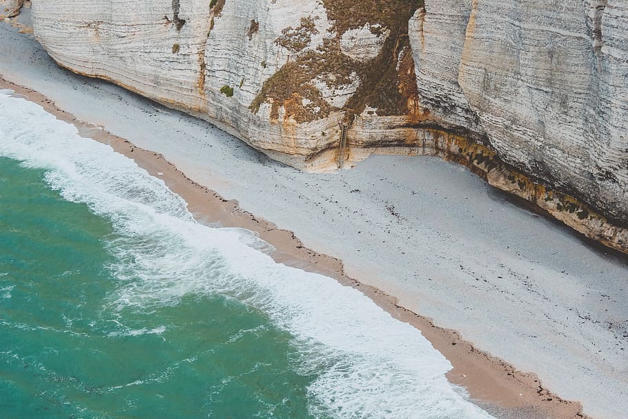 bird's eye view photo of seashore beside cliff, aerial photo of gray seashore near gray cliff during daytime HD wallpaper