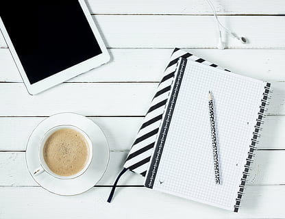 black pen on top of white notebook beside white teacup, tablet HD wallpaper