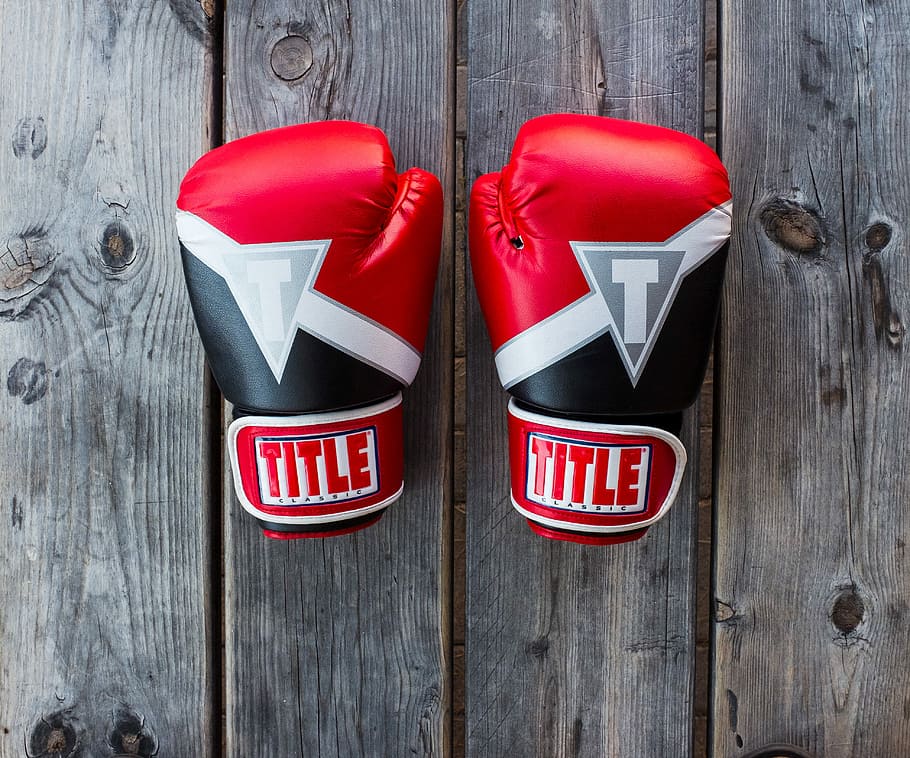pair of red-and-black Title training gloves on grey wooden plank, red-and-black Title boxing gloves