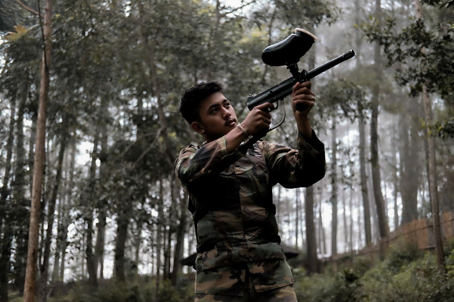 Take a steady shot, man holding black paintball gun near trees, HD wallpaper