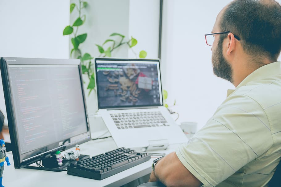 man sitting in front of computer monitor and laptop, turned on flatscreen computer monitor HD wallpaper
