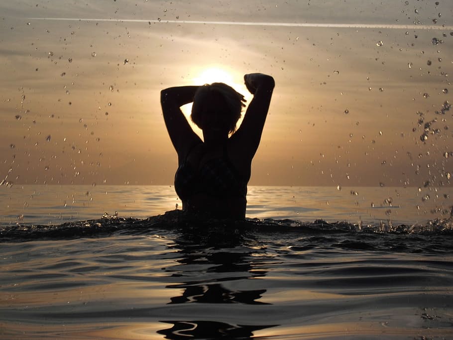 woman in water during golden hour, sea, swim, silhouette, sun