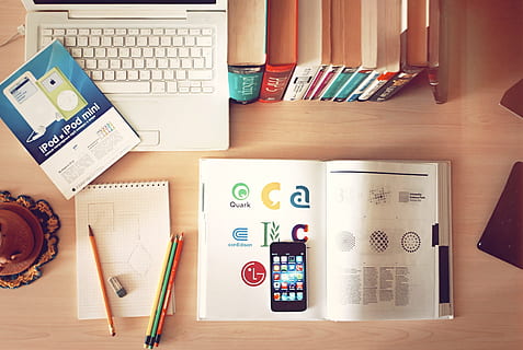 black iPhone on top of open book beside laptop and notebooks on table HD wallpaper