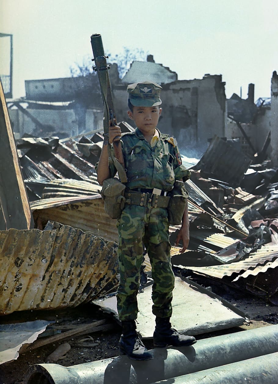 boy holding gun, young child, sad, soldier, war, viet nam, 1968