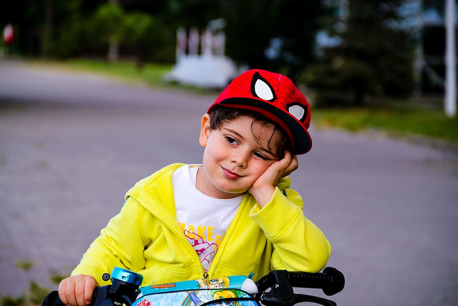 boy wearing yellow zip-up jacket and spiderman cap, child, bicycle
