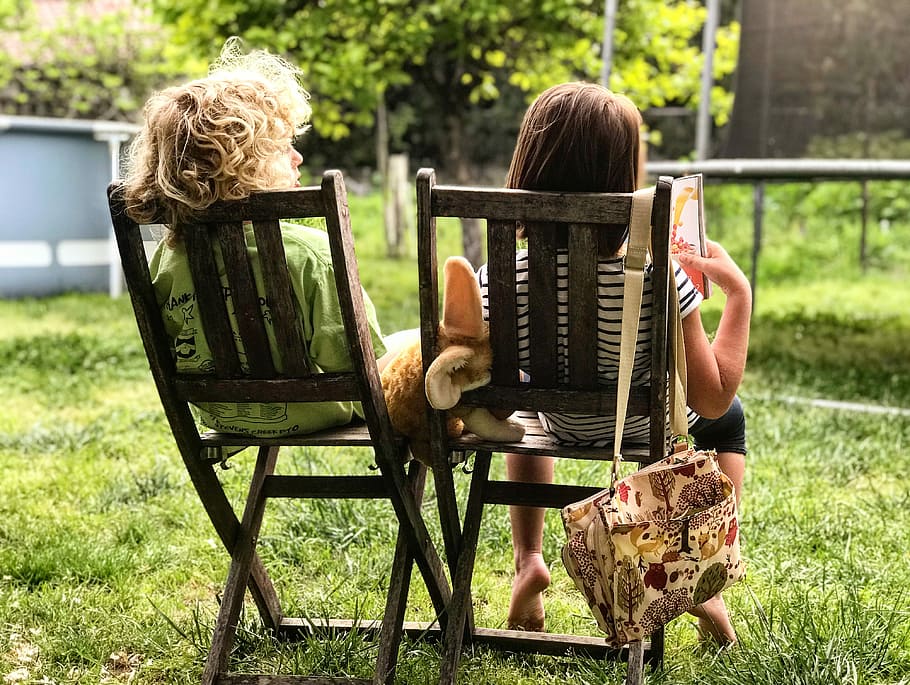 two children sitting on chairs, two children sitting on black wooden chairs