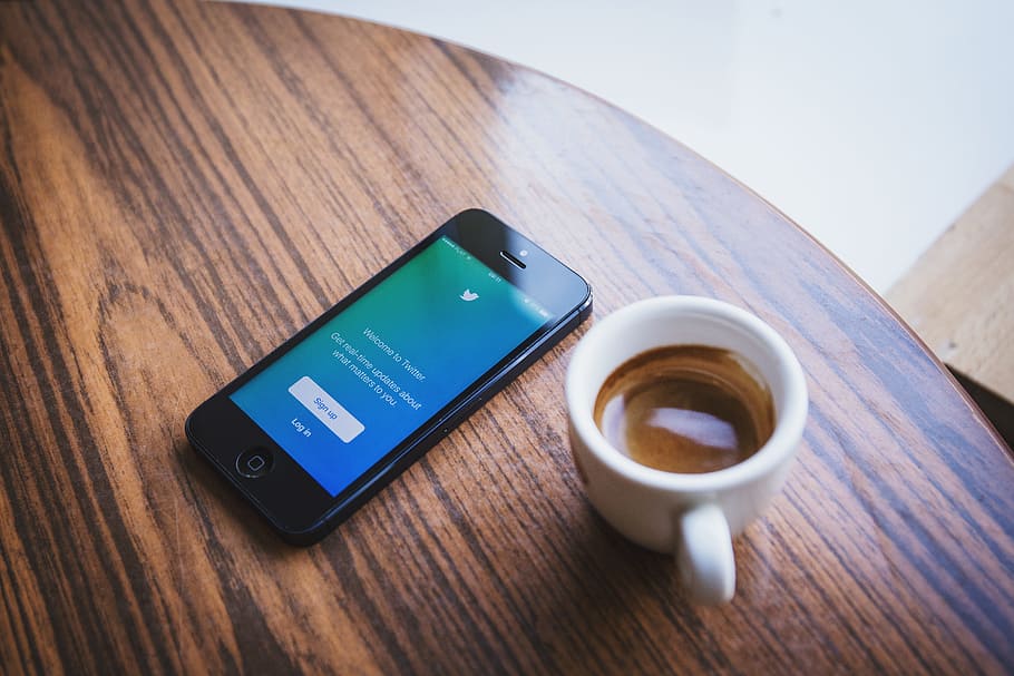 black iPhone 5 beside cup on tabletop, twitter, social media