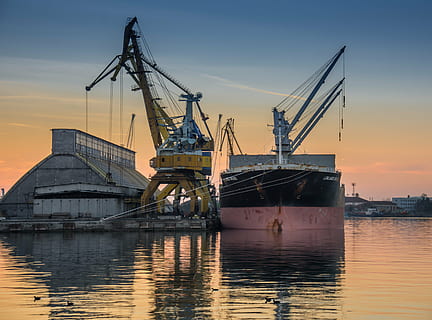 two yellow and gray heavy equipments on calm water during golden hour HD wallpaper