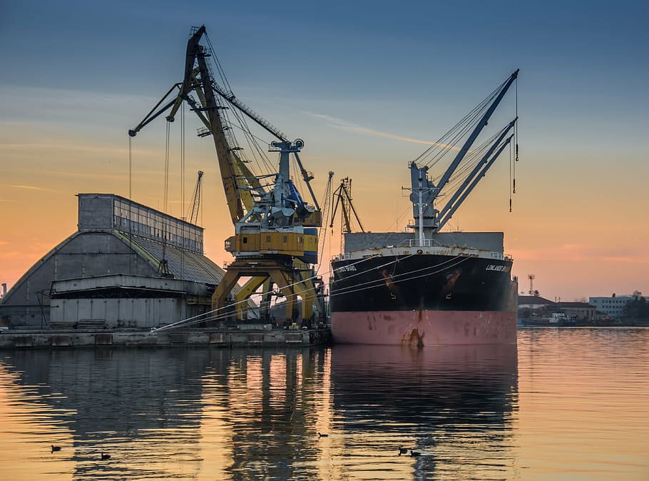 two yellow and gray heavy equipments on calm water during golden hour HD wallpaper