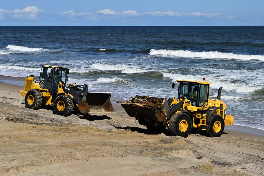 two yellow frontloaders on shorte, hurricane matthew, damage HD wallpaper