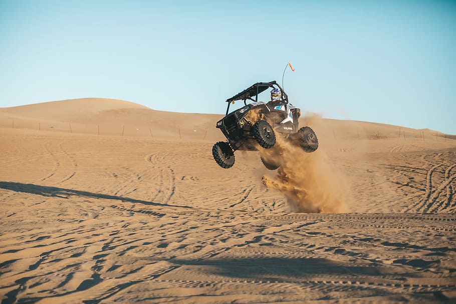 man riding on UTV on desert during daytime, black dune buggy on desert