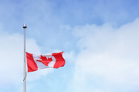 Canada flag rising on pole under white clouds during daytime HD wallpaper