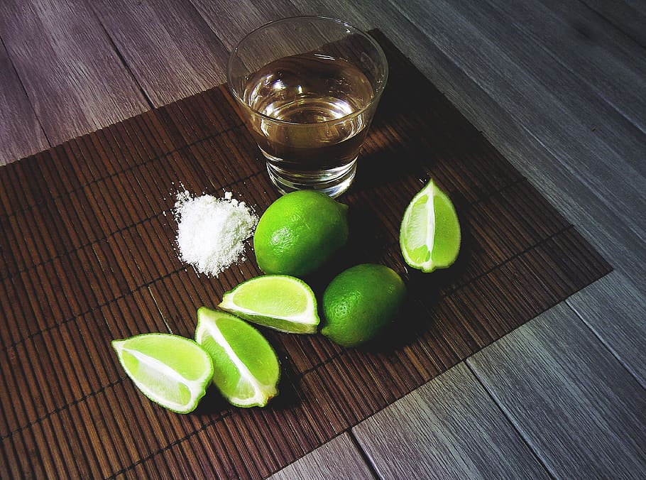 clear shot glass filled with liquid substance beside sliced lime HD wallpaper