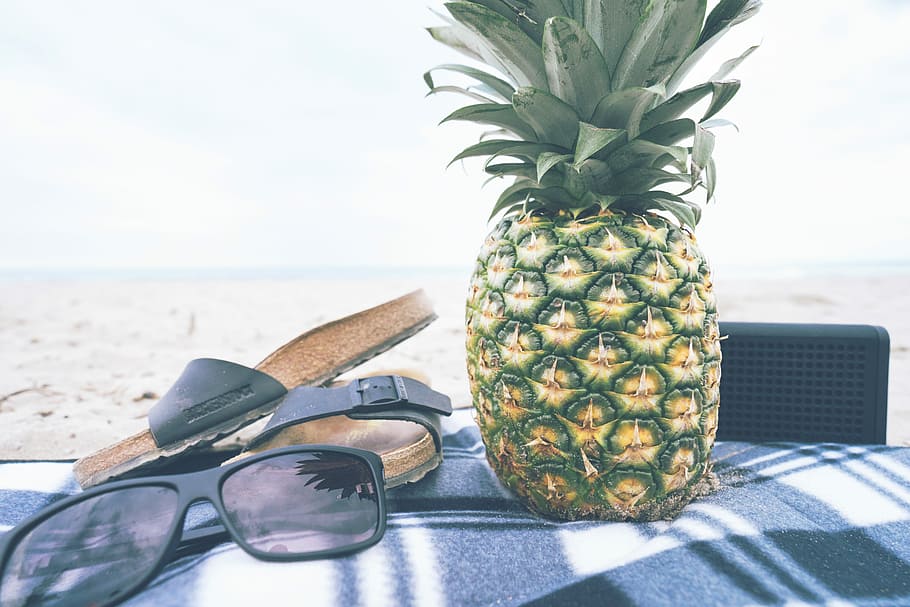 green and yellow pineapple besides black slide slippers and sunglasses, pineapple on blue,black, and white textile HD wallpaper