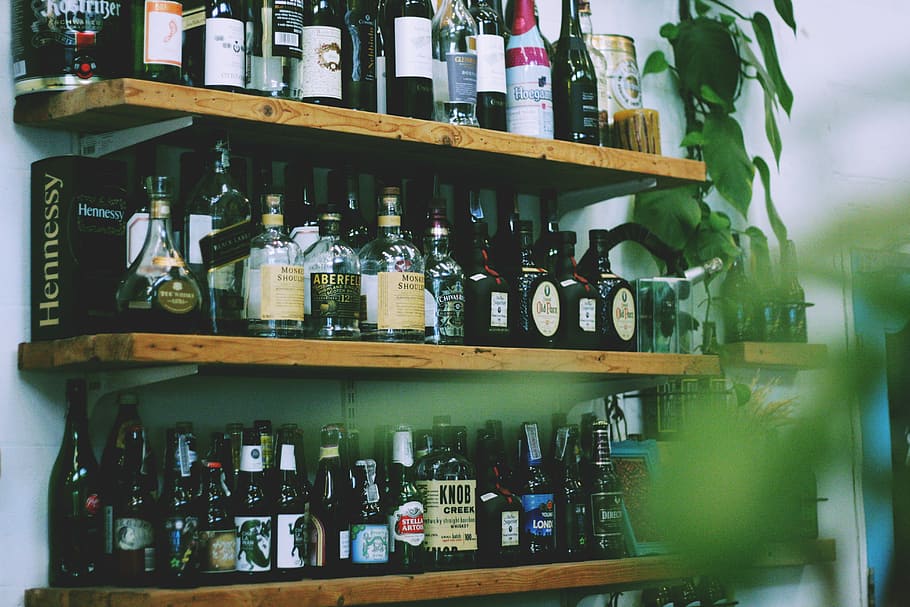 liquor bottles on brown wooden shelves closeup photography, bottles on rack HD wallpaper