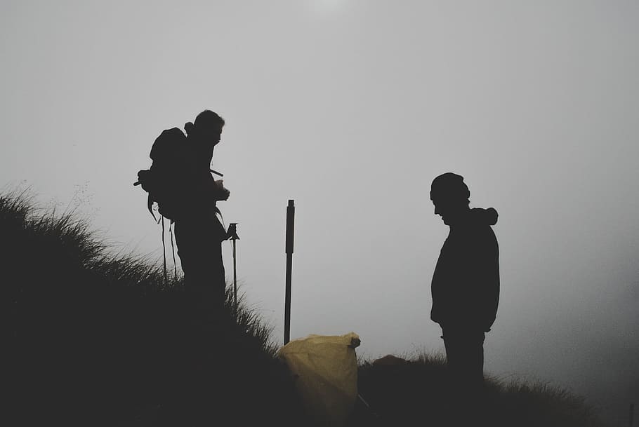 silhouette photo of two men climbing mountain, two person on grass field during fog HD wallpaper