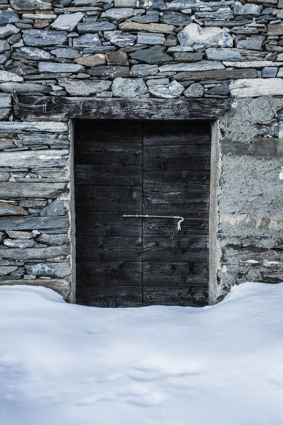 two black wooden doors behind snow, gray stone house with black wooden door HD wallpaper