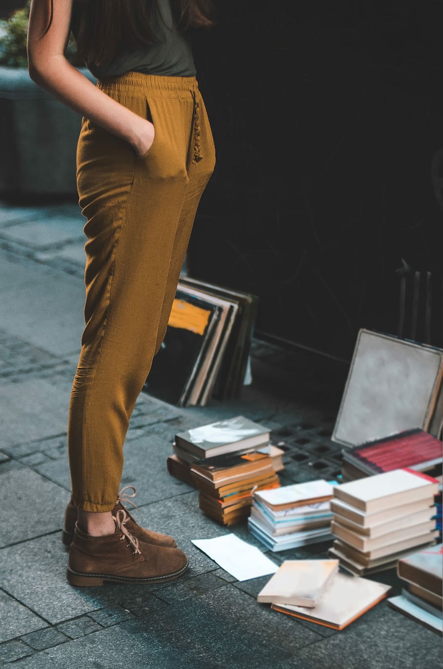person wearing brown pants beside assorted book lot, person wearing brown jogger pants facing assorted photo frames