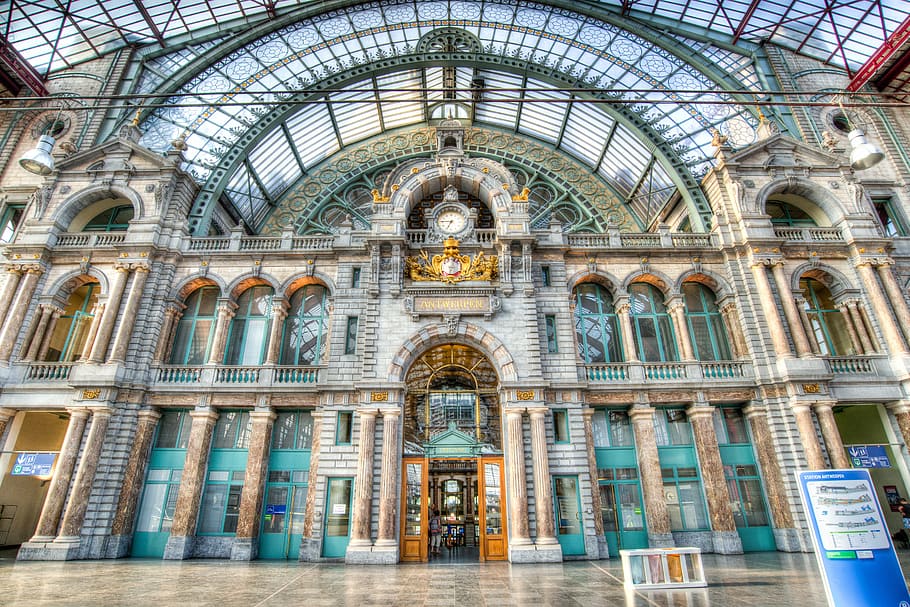 gray and teal concrete building with tower clock, antwerp, station