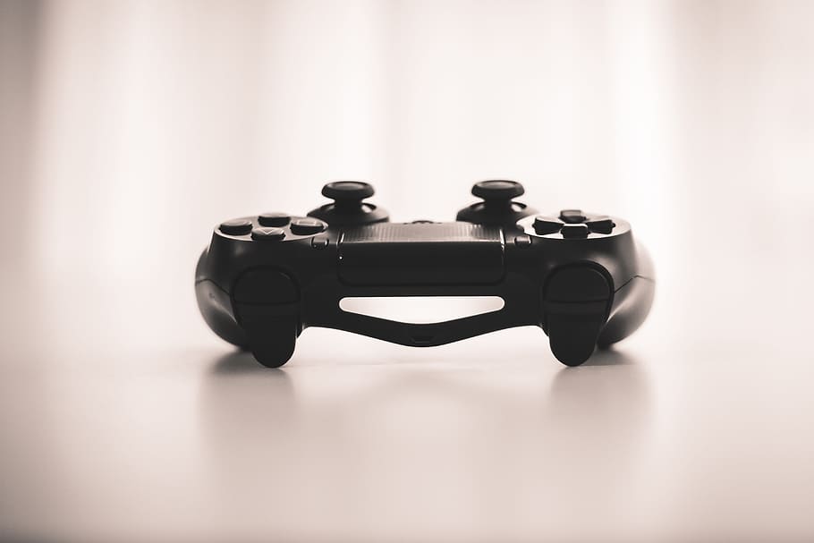 black wireless game controller, selective focus photo of black cordless game controller on top of white surface