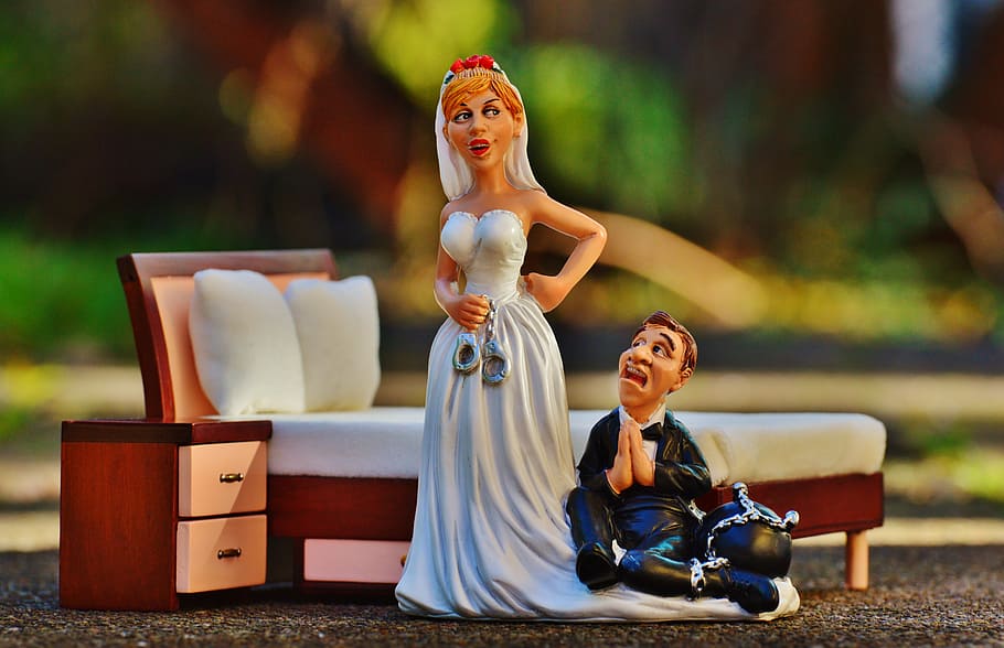 married couple figurine beside bed frame selective focus photography