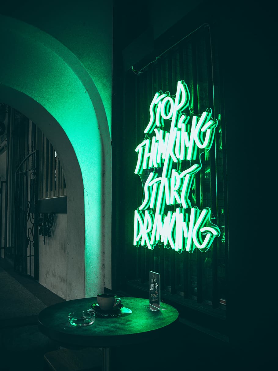 turned-on neon signage, green stop thinking start drinking neon signage beside round black table
