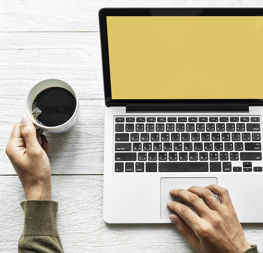 person holding a cup of coffee while using MacBook Pro, analysis