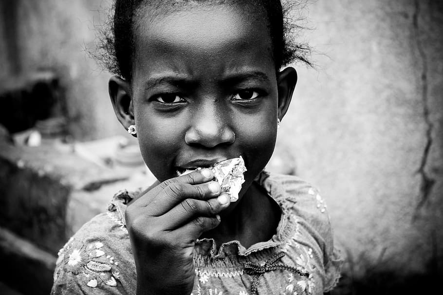 grayscale photo of girl eating food, african child, joy, deep look