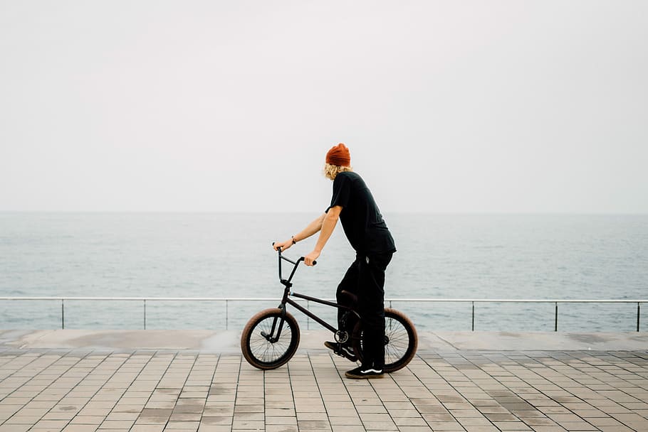 man holding BMX bike, man looking at sea while holding bicycle