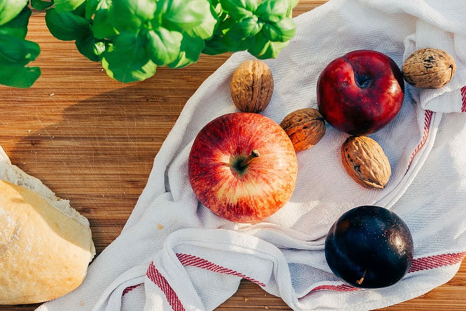 two apples and walnuts on white towel, two red apples beside brown nuts on white handkercheif HD wallpaper