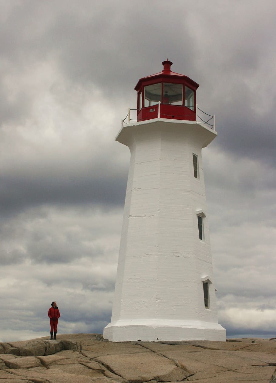 person standing beside white and red lighthouse, ocean, coast