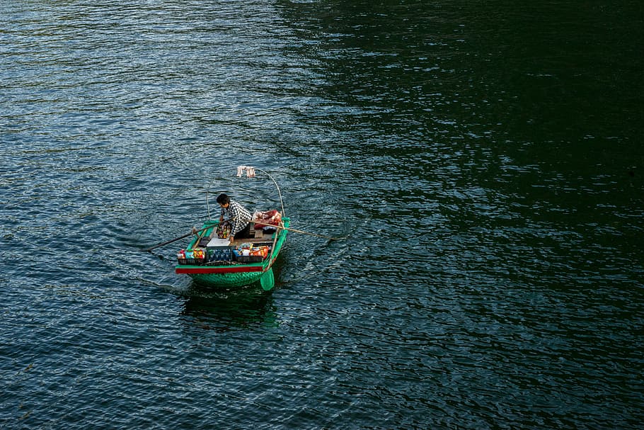 person on green boat, person riding jon boat on calm body of water