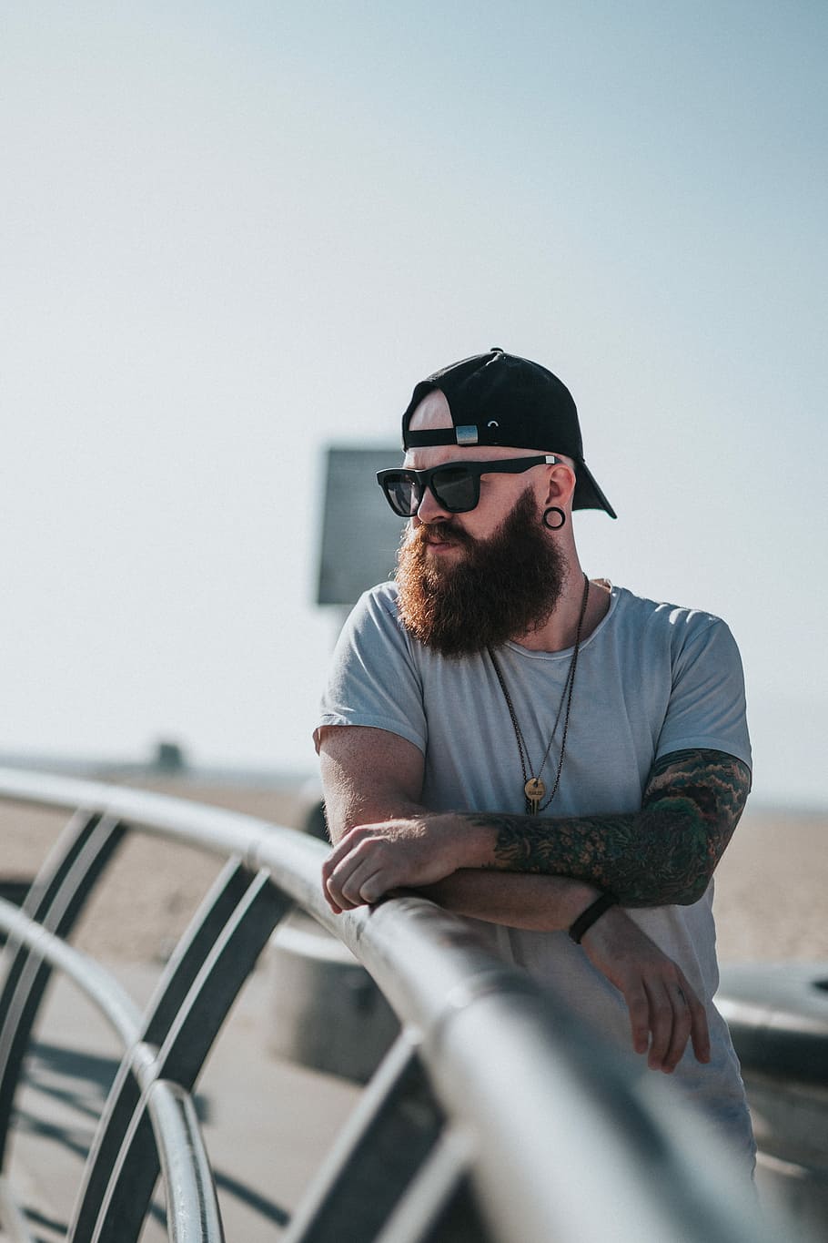 shallow focus photography of man wearing black wayfarer sunglasses, man standing beside metal fence HD wallpaper