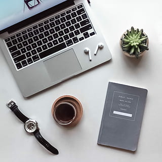 flat-lay photography of MacBook, coffee-filled cup, book, and wristwatch, white Apple AirPods on top MacBook Pro HD wallpaper