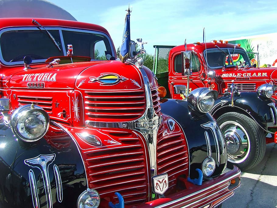 two red Dodge Victoria and Noble Charm trucks under blue sky during daytime