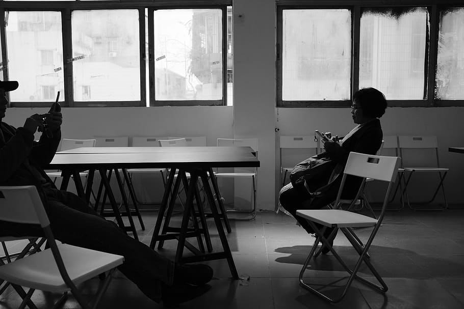 grayscale photo of two person sitting on chair inside the room, twp persons sitting in classroom HD wallpaper