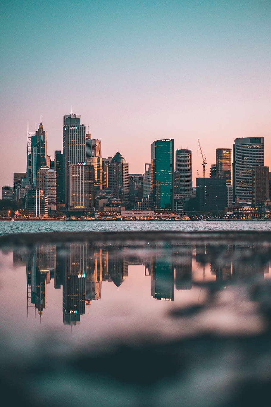city buildings during daytime, city skyline reflected on calm body of water HD wallpaper