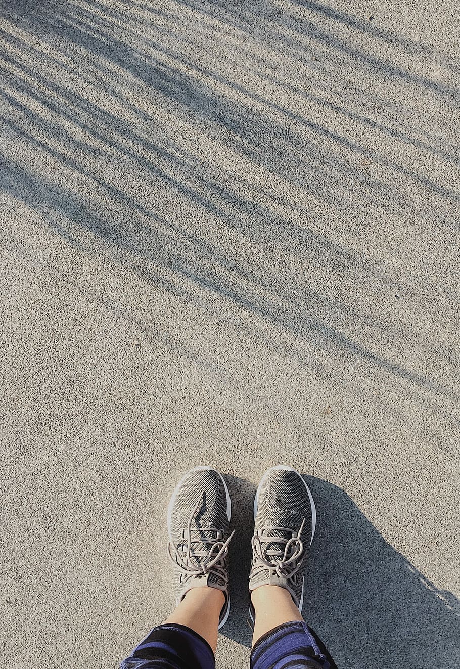 person wearing paint of gray running shoes, person standing on gray sand HD wallpaper
