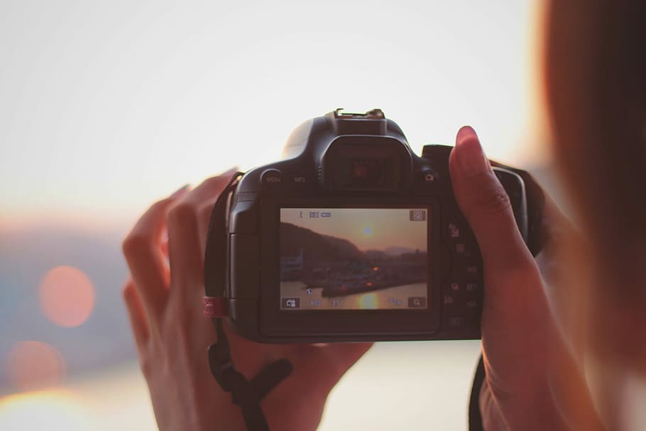 person holding a DSLR camera while taking a photo of an island HD wallpaper
