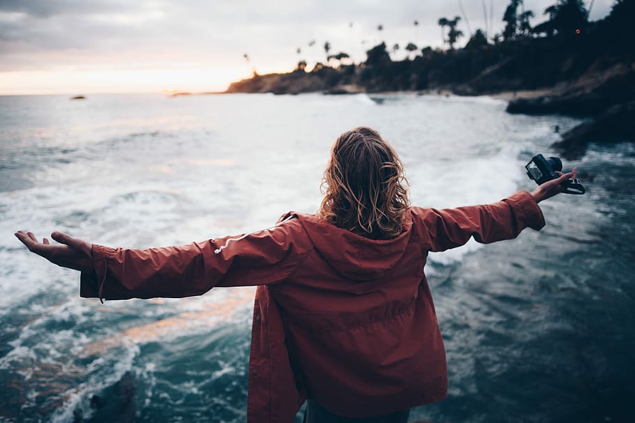 person standing near body of water, woman facing ocean open arms at daytime HD wallpaper