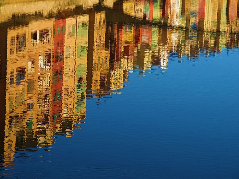 assorted-color building reflecting on body of water at daytime HD wallpaper
