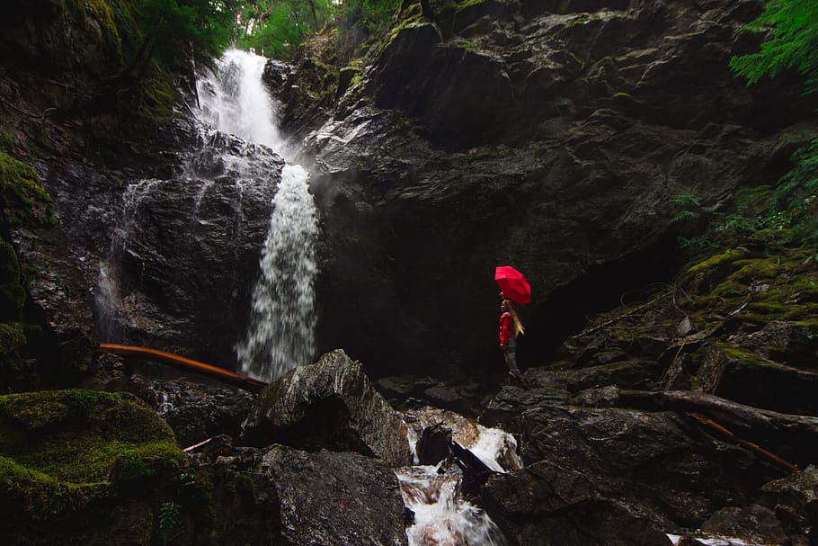 person standing on rock formation under red umbrella beside waterfalls, person standing near water falls HD wallpaper