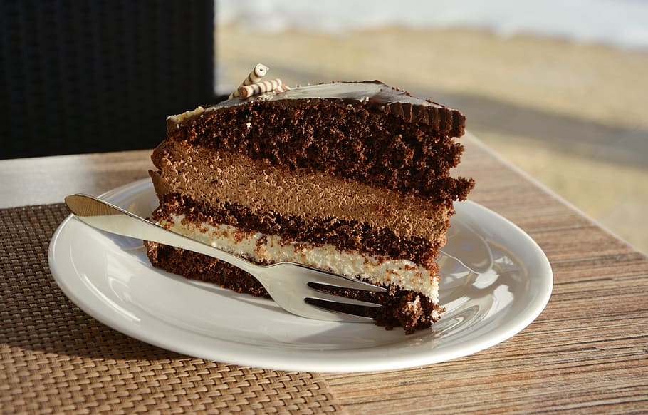 slice of cake on round white ceramic saucer on brown wooden surface HD wallpaper