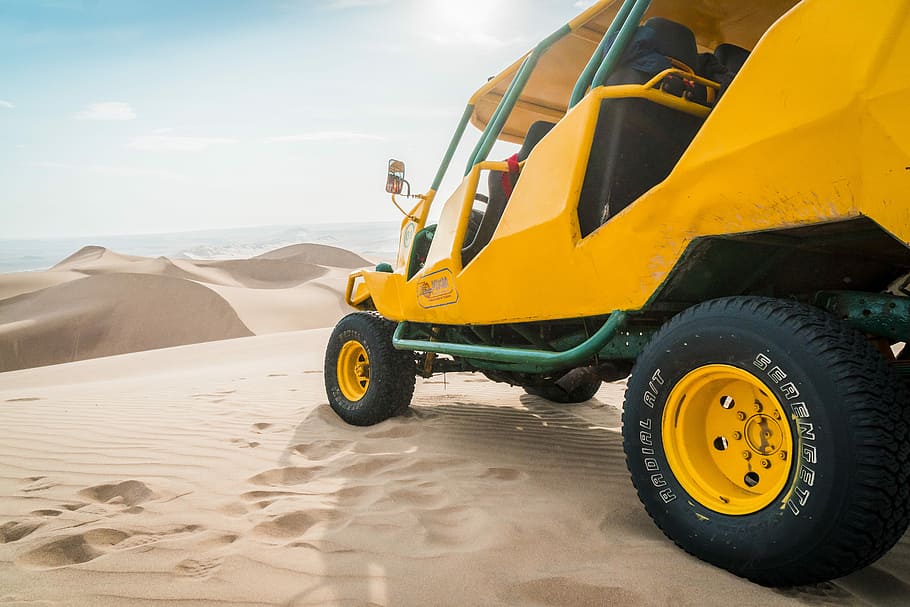 yellow and green UTV parked on a desert field, yellow and black ATV on desert