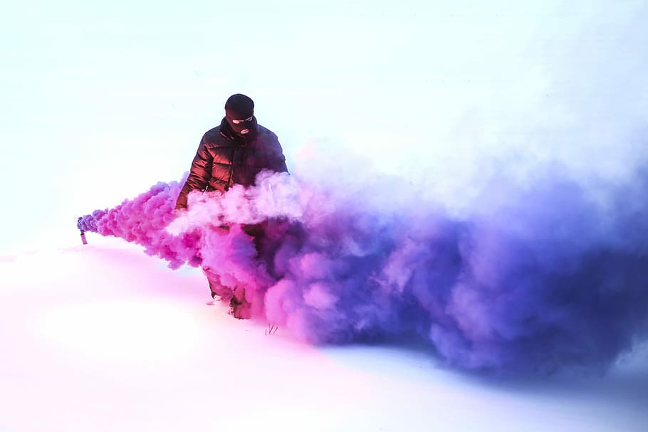 person walking on purple smoke, man wearing black bubble jacket and surrounded smoke