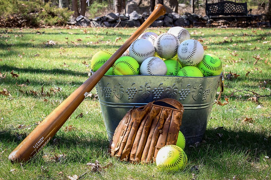 baseball lot on bucket beside baseball bat and gloves, grass