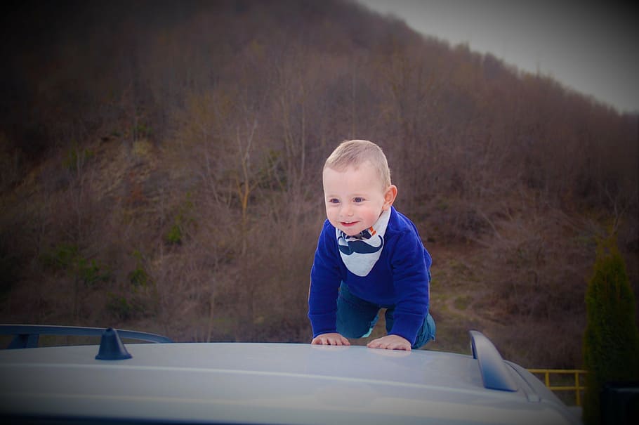 boy crawling on top of white vehicle at daytime, baby, child