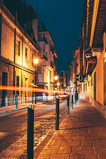 time-lapse photography of vehicle passing on the road between street lights and buildings during night time, scenery of city buildings HD wallpaper