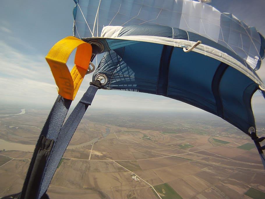 blue and white parachute above brown ground under blue and white clouds during daytime HD wallpaper